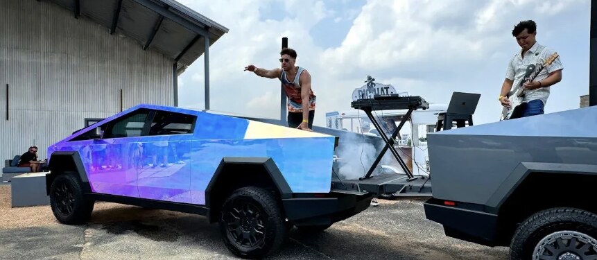 A wrapped Tesla Cybertruck beside a DJ and guitarist performing at an outdoor Cybertruck Rodeo gathering