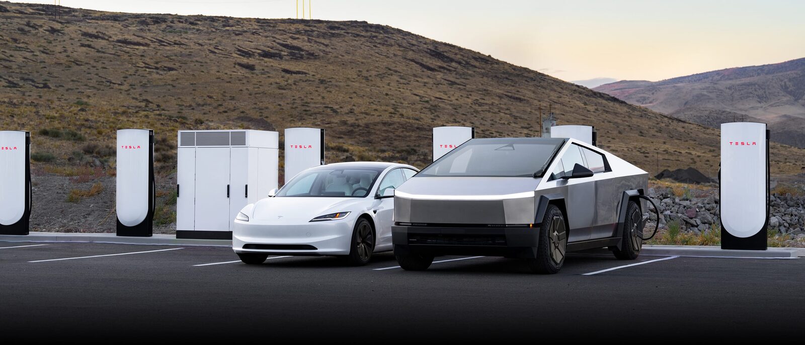 A Tesla Model 3 and Cybertruck parked at a Tesla Supercharger station in the hills at dusk